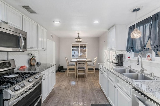 kitchen featuring sink, hanging light fixtures, white cabinets, and stainless steel appliances