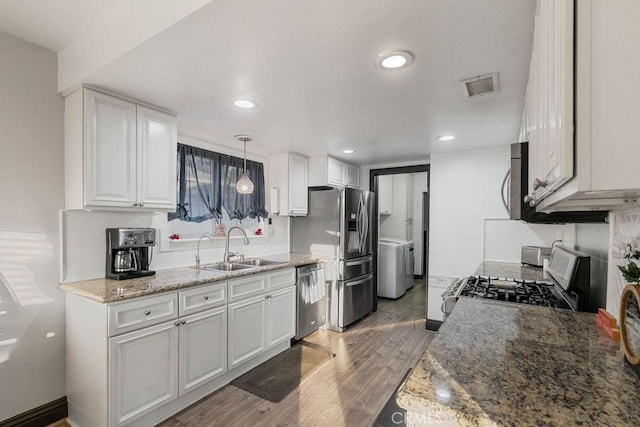 kitchen featuring appliances with stainless steel finishes, sink, white cabinetry, and decorative light fixtures