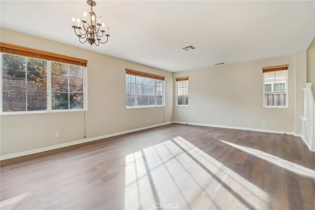 spare room featuring hardwood / wood-style floors and a notable chandelier