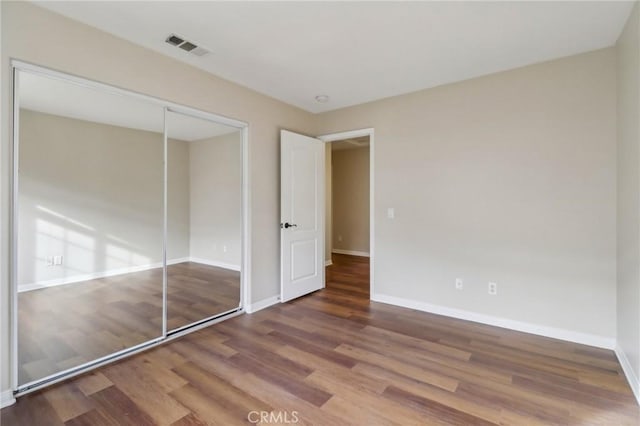 unfurnished bedroom with hardwood / wood-style flooring and a closet