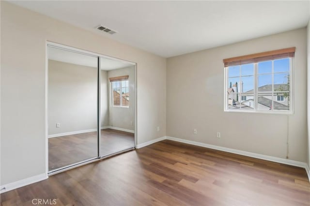 unfurnished bedroom featuring a closet, multiple windows, and hardwood / wood-style floors