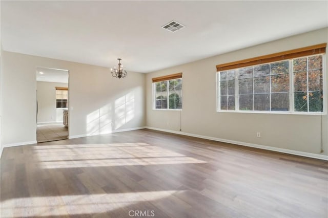 unfurnished room with a chandelier and light hardwood / wood-style floors