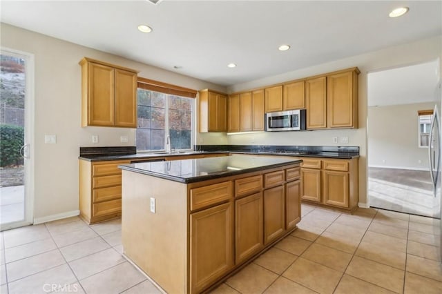 kitchen with light tile patterned floors, appliances with stainless steel finishes, a center island, and sink