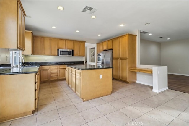 kitchen featuring dark stone countertops, a center island, light tile patterned flooring, sink, and stainless steel appliances