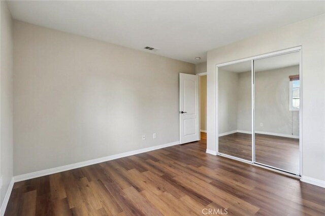 unfurnished bedroom with a closet and dark wood-type flooring