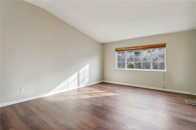 empty room with hardwood / wood-style floors and lofted ceiling