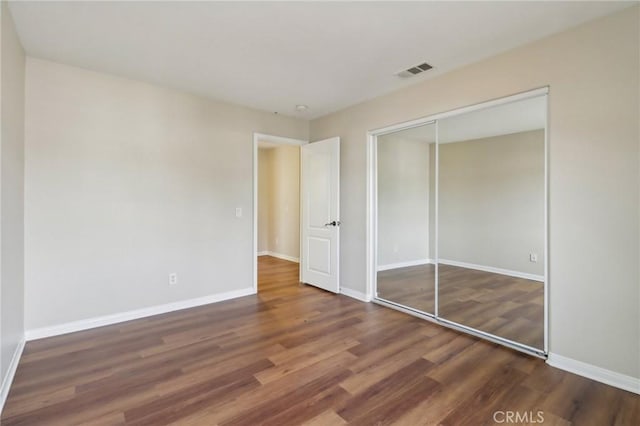 unfurnished bedroom featuring a closet and dark wood-type flooring