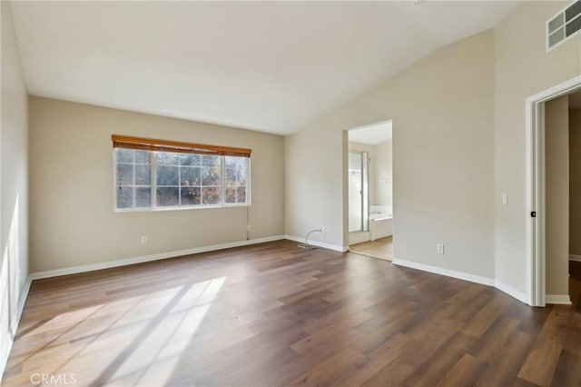 spare room featuring wood-type flooring and vaulted ceiling