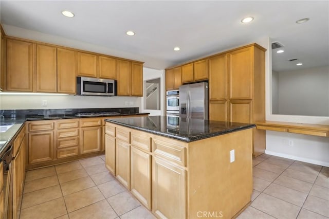 kitchen featuring dark stone countertops, light tile patterned floors, appliances with stainless steel finishes, and a kitchen island