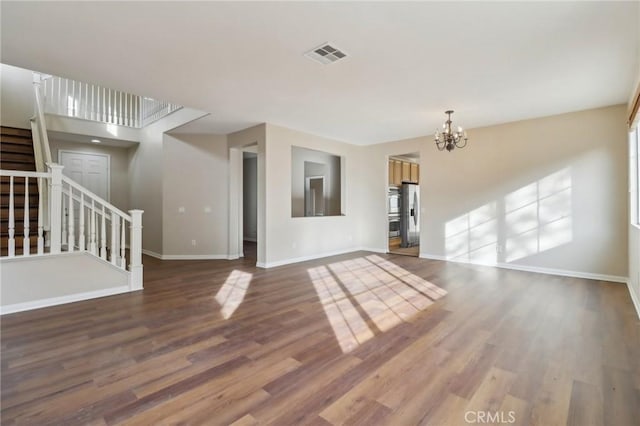 unfurnished living room with wood-type flooring and a chandelier