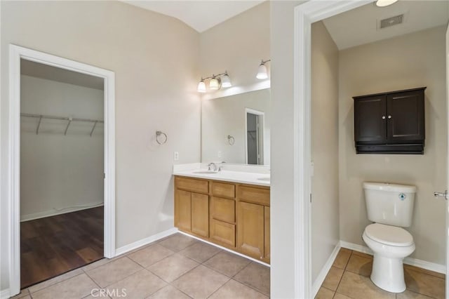 bathroom with toilet, vanity, and tile patterned floors