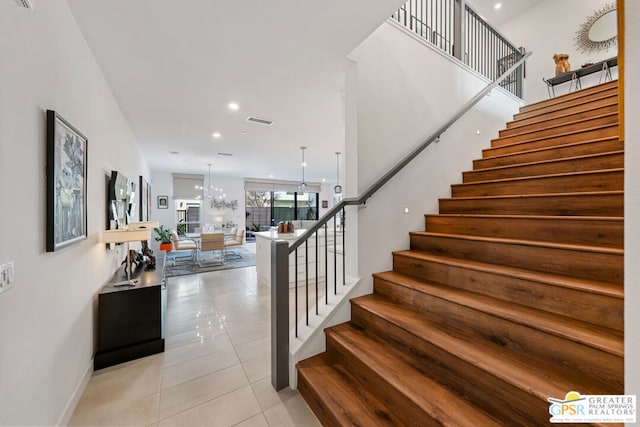 stairs featuring an inviting chandelier and tile patterned flooring