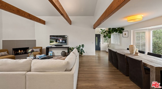 living room with dark wood-type flooring, beam ceiling, and a tiled fireplace