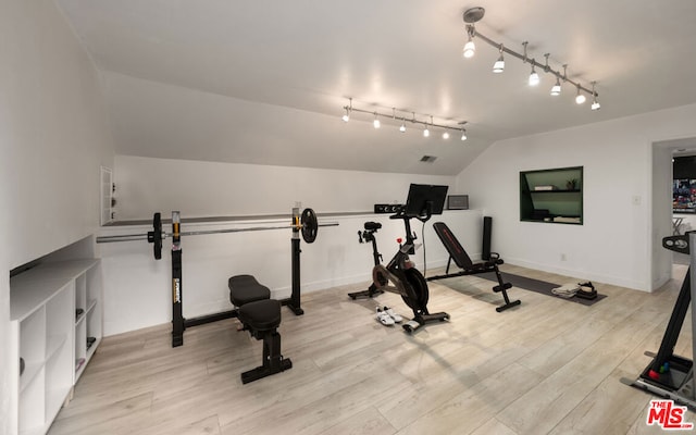 exercise room with lofted ceiling and light hardwood / wood-style flooring