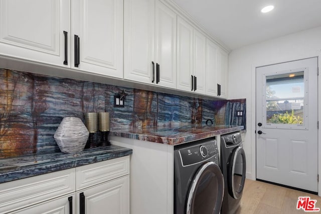 clothes washing area featuring light wood-type flooring, cabinets, and washer and clothes dryer