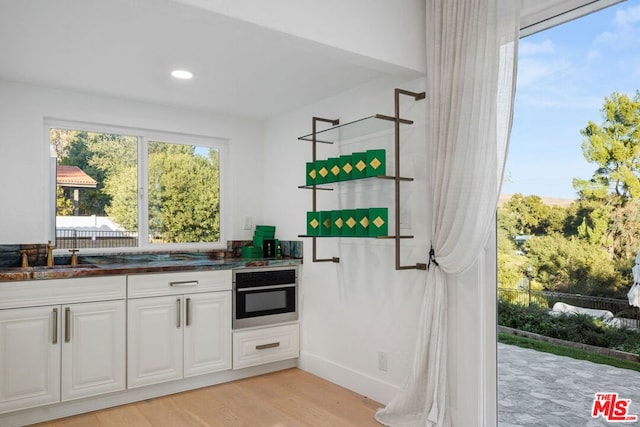 kitchen featuring sink, white cabinetry, oven, and light wood-type flooring