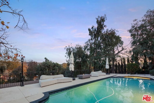 pool at dusk featuring a patio area