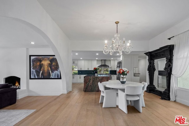 dining space featuring a high end fireplace, a chandelier, and light hardwood / wood-style floors