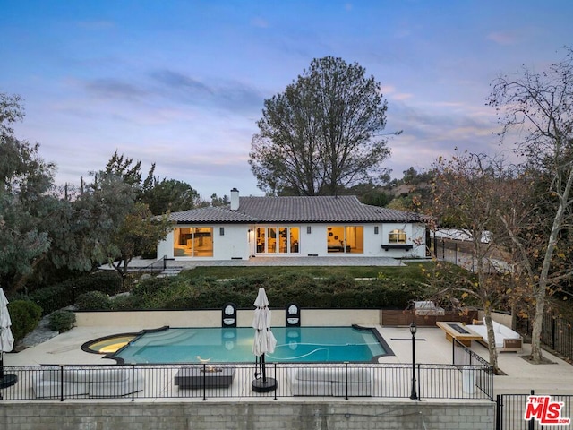 pool at dusk featuring a patio area