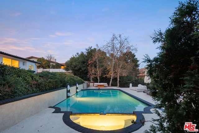 pool at dusk featuring a patio area