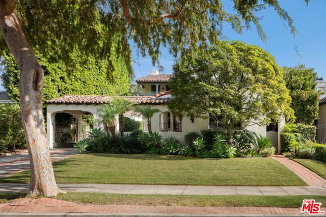 mediterranean / spanish house with a front lawn and a carport