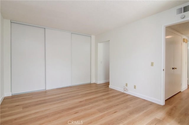 unfurnished bedroom with a closet and light hardwood / wood-style floors