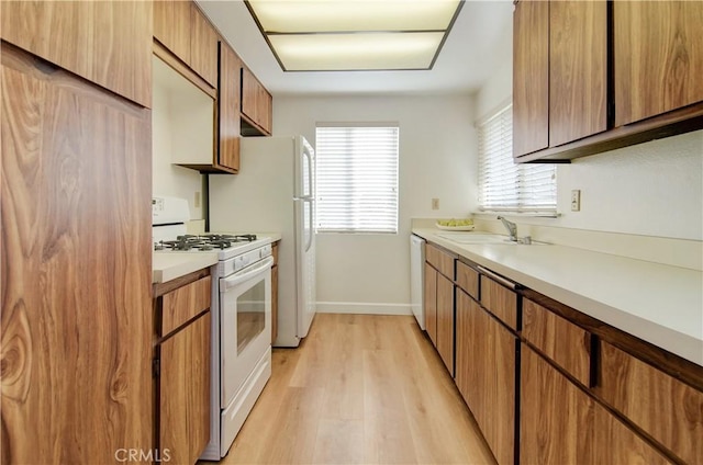 kitchen featuring sink, light hardwood / wood-style flooring, and white appliances