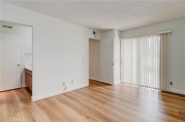 spare room with a textured ceiling and light hardwood / wood-style floors