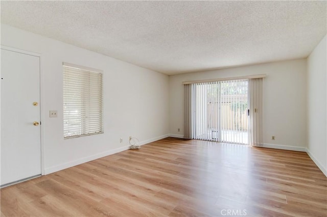 unfurnished room with light wood-type flooring and a textured ceiling