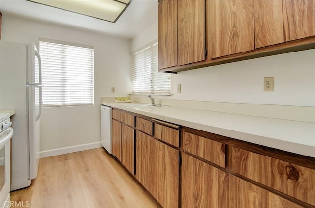 kitchen with white appliances, light hardwood / wood-style floors, and sink