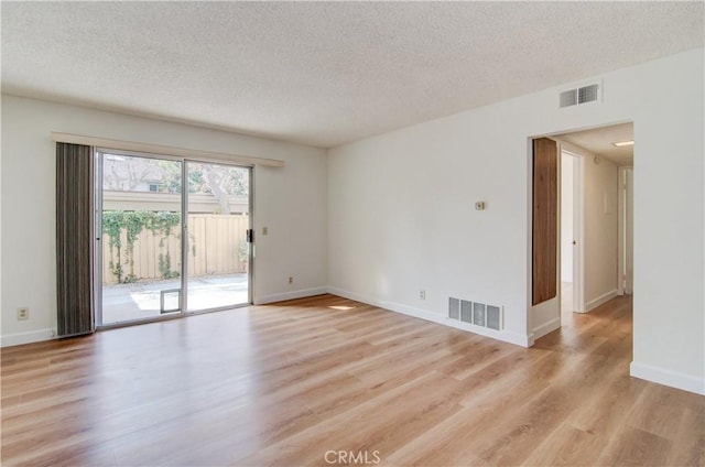 spare room featuring a textured ceiling and light hardwood / wood-style floors