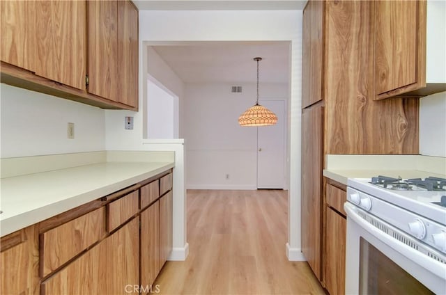 kitchen with light wood-type flooring, white stove, and decorative light fixtures