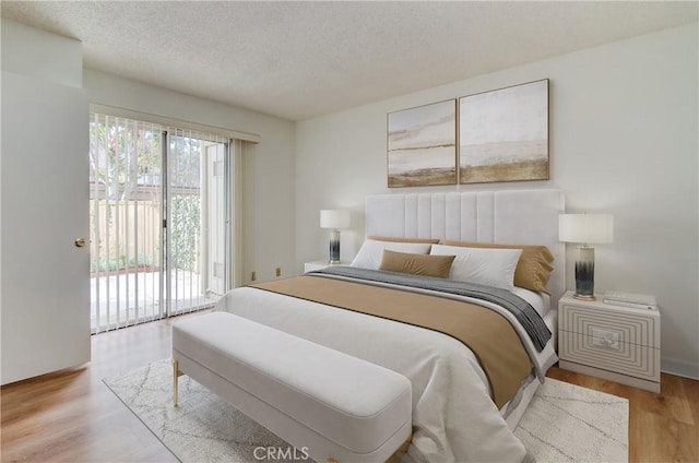 bedroom featuring light wood-type flooring, access to exterior, and a textured ceiling