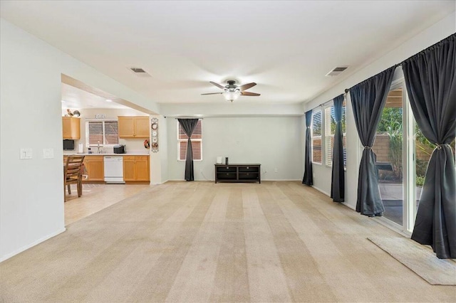 living room featuring light carpet, ceiling fan, and sink