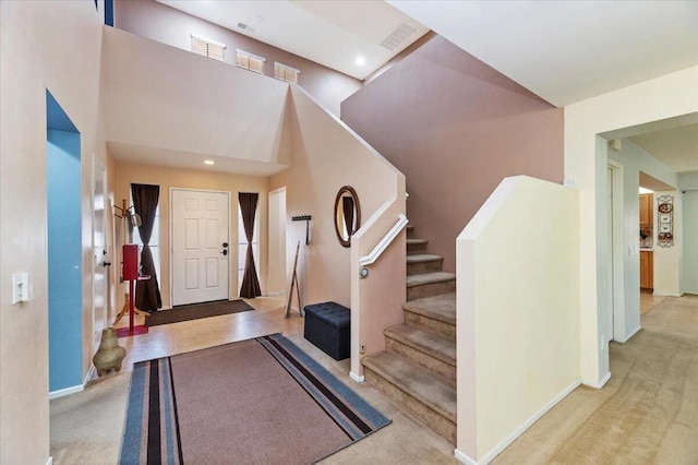 foyer entrance with a high ceiling and light carpet