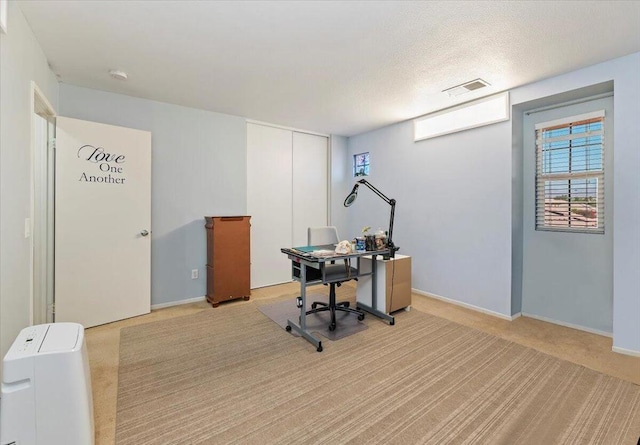 office space with a textured ceiling and light colored carpet