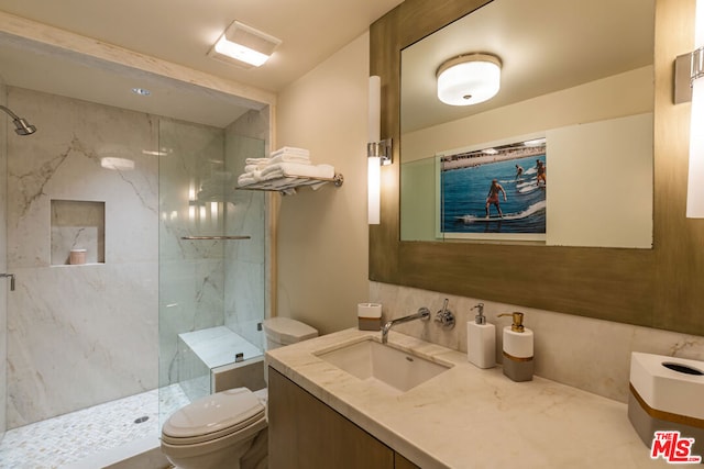 bathroom featuring tiled shower, vanity, and toilet