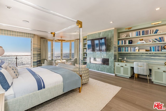 bedroom with a water view, wood-type flooring, and multiple windows