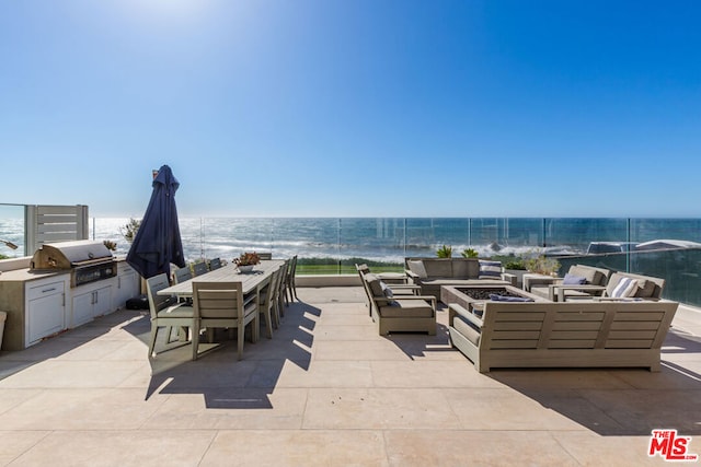 view of patio with a grill, an outdoor living space with a fire pit, a water view, and a beach view