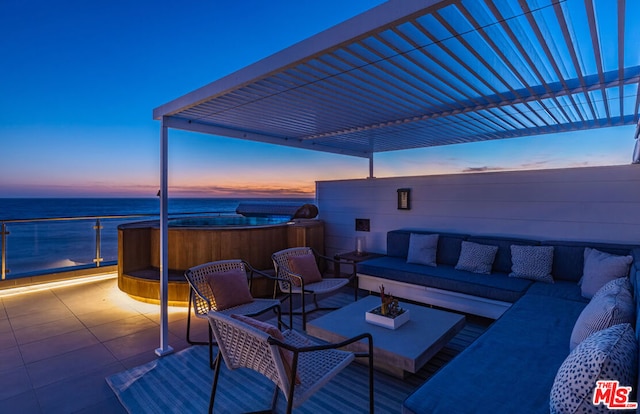 patio terrace at dusk with a hot tub, an outdoor living space, and a water view