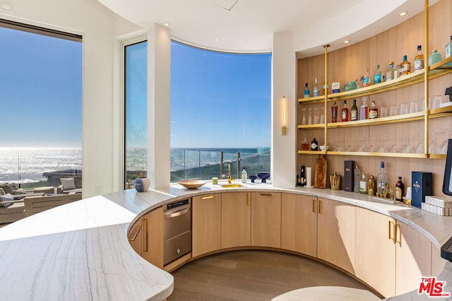 bar featuring hardwood / wood-style floors, a water view, light brown cabinets, and sink