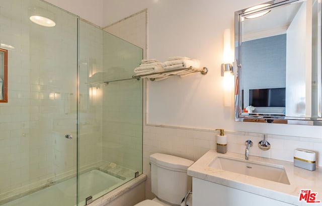 full bathroom with toilet, vanity, tile walls, and shower / bath combination with glass door