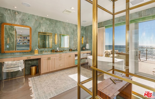 bathroom with a bath, floor to ceiling windows, a water view, and vanity