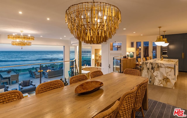 dining area with a chandelier, hardwood / wood-style floors, a water view, and a view of the beach