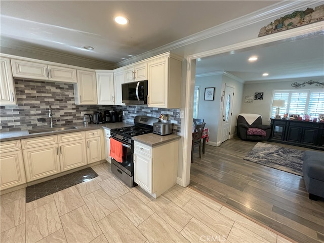 kitchen with sink, light hardwood / wood-style flooring, decorative backsplash, crown molding, and appliances with stainless steel finishes