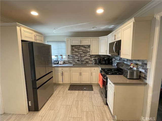 kitchen featuring sink, fridge, stainless steel range with gas cooktop, ornamental molding, and backsplash