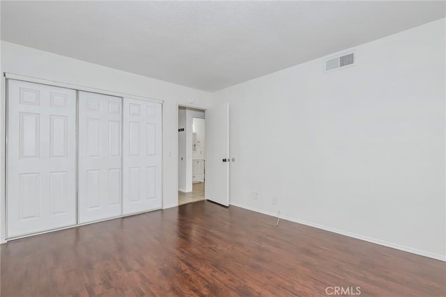 unfurnished bedroom with a closet and dark hardwood / wood-style flooring