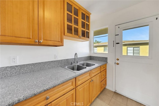 kitchen with light tile patterned floors, sink, and light stone counters