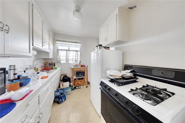 kitchen with white cabinets, range with gas cooktop, sink, refrigerator, and light hardwood / wood-style flooring