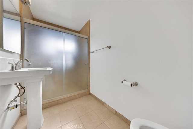 bathroom featuring toilet, a shower with door, and tile patterned flooring